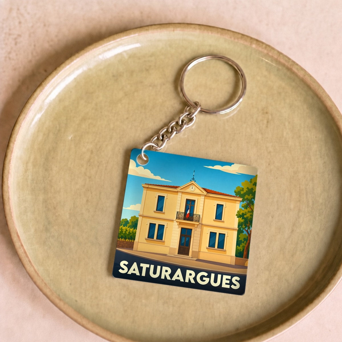 Porte-clés souvenir de la ville de Saturargues avec une illustration stylisée de sa mairie.