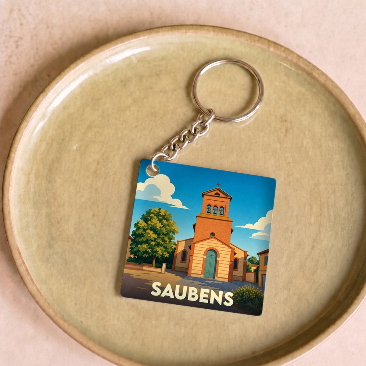 Porte-clés souvenir de la ville de Saubens avec une illustration stylisée de son église.
