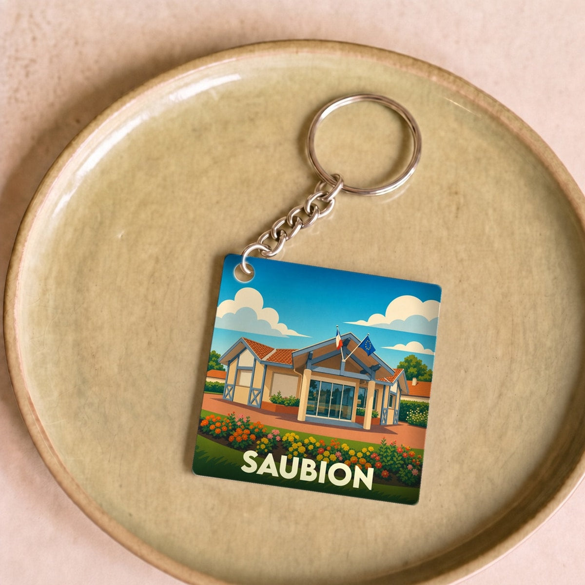 Porte-clés souvenir de la ville de Saubion avec une illustration stylisée.