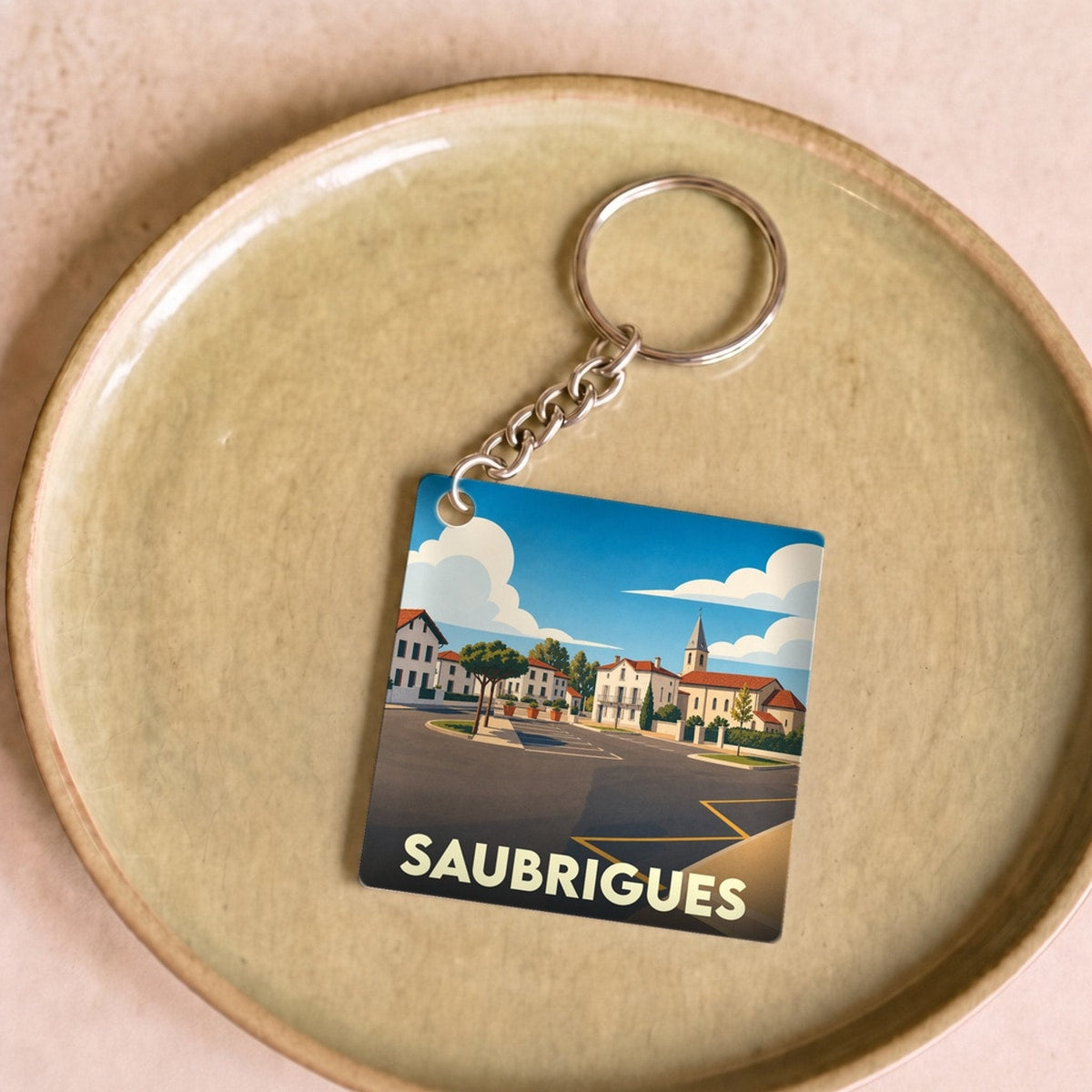 Porte-clés souvenir de la ville de Saubrigues avec une illustration stylisée.