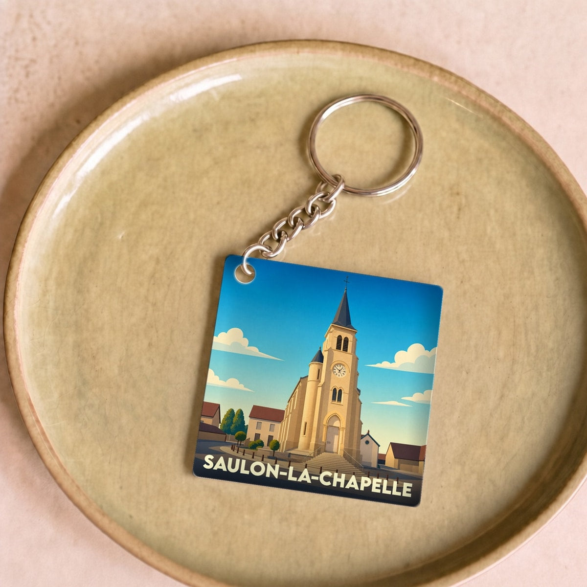 Porte-clés souvenir de la ville de Saulon-la-Chapelle avec une illustration stylisée de son église.