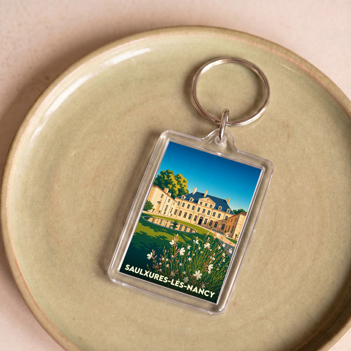 Porte-clés souvenir de la ville de Saulxures-lès-Nancy avec une illustration stylisée de son château.