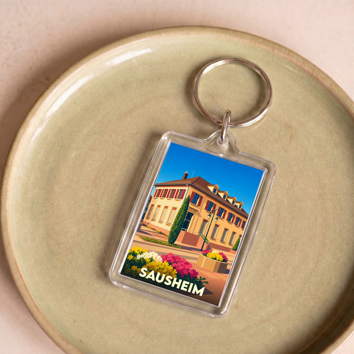 Porte-clés souvenir de la ville de Sausheim avec une illustration colorée et stylisée de sa mairie.