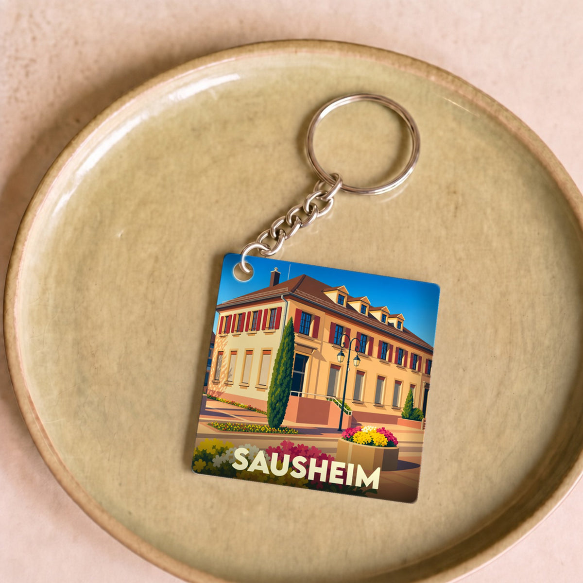 Porte-clés souvenir de la ville de Sausheim avec une illustration colorée et stylisée de sa mairie.
