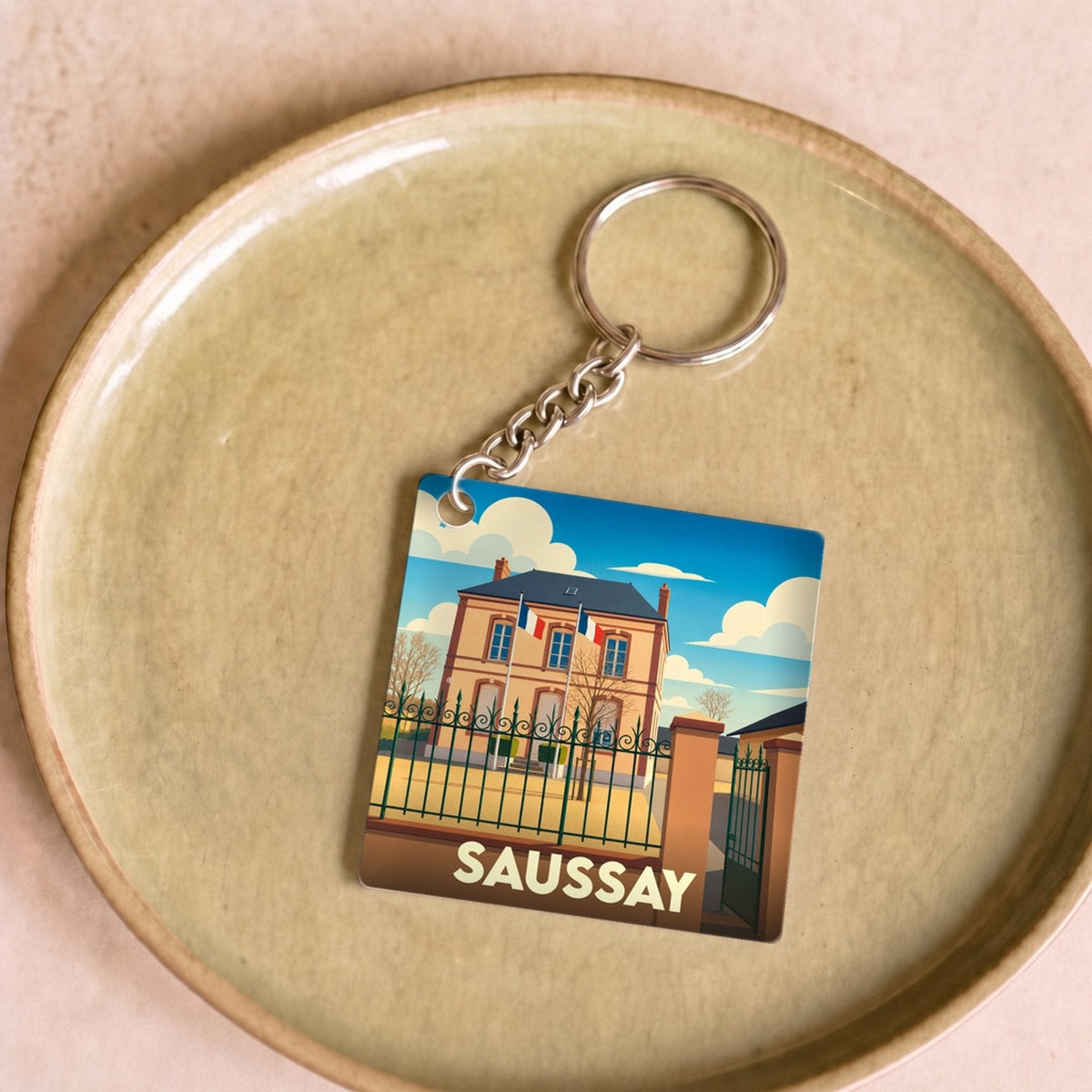 Porte-clés souvenir de la ville de Saussay avec une illustration stylisée de la mairie.