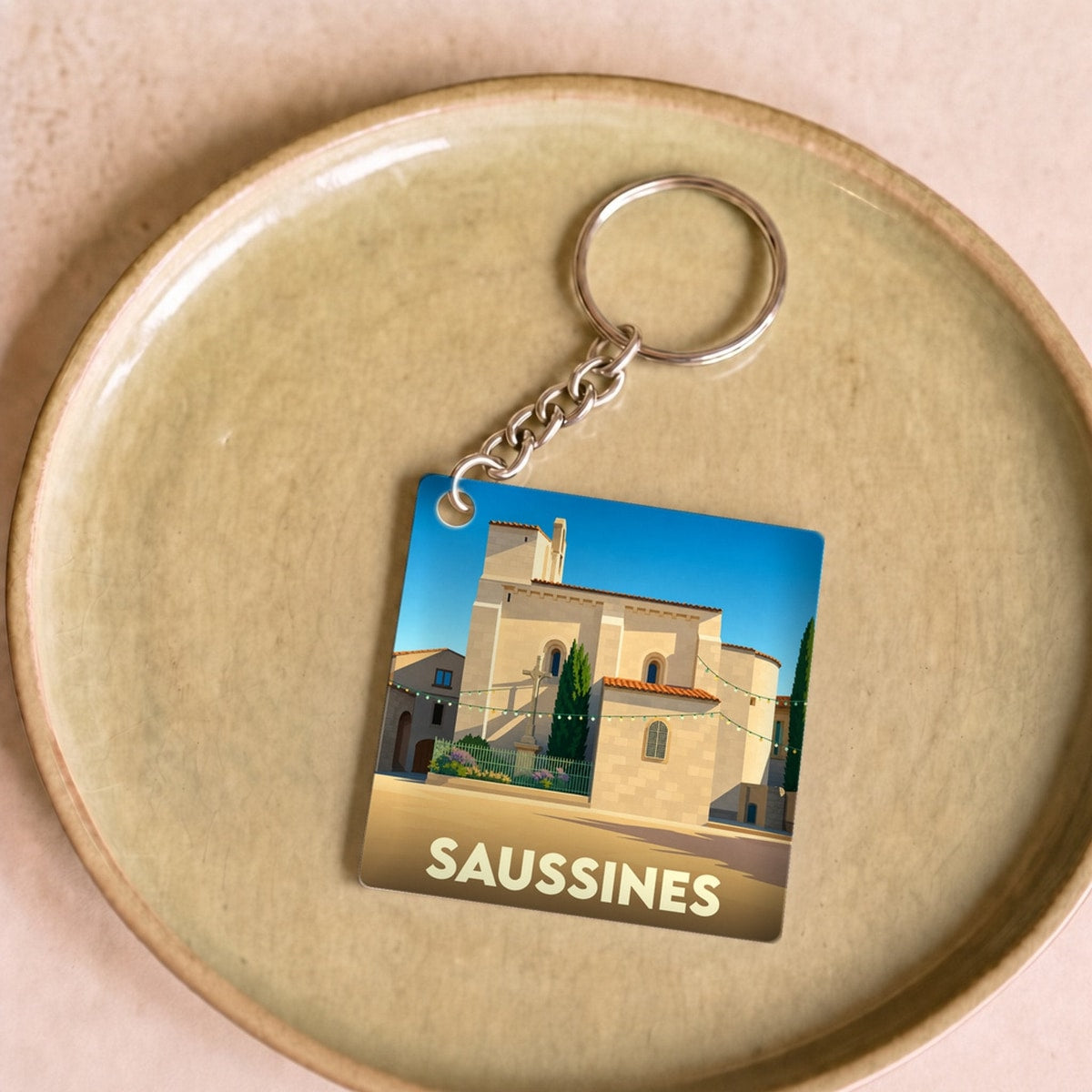Porte-clés souvenir de la ville de Saussines avec une illustration stylisée de son église.