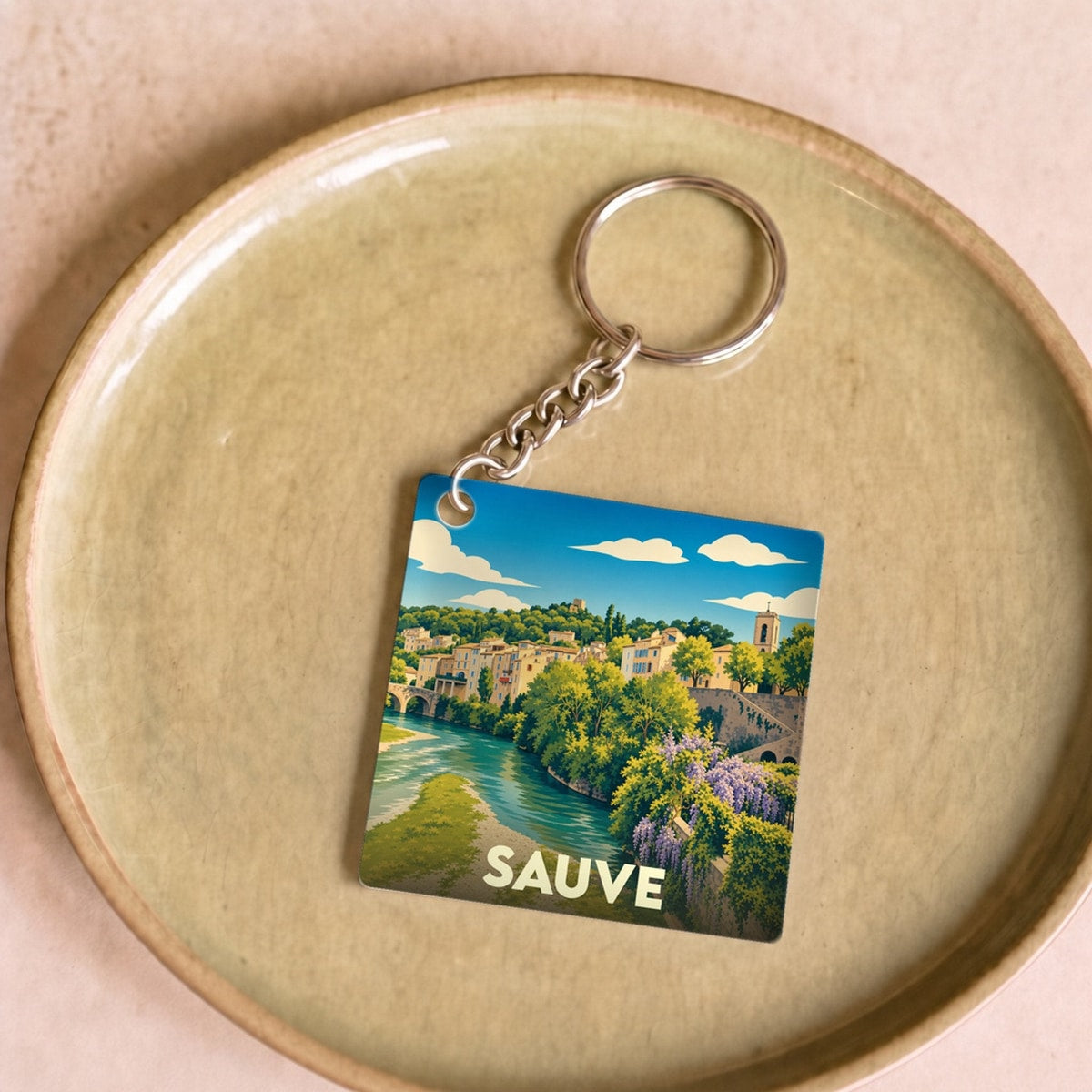 Porte-clés souvenir de la ville de Sauve avec une illustration stylisée d'un paysage fluvial.