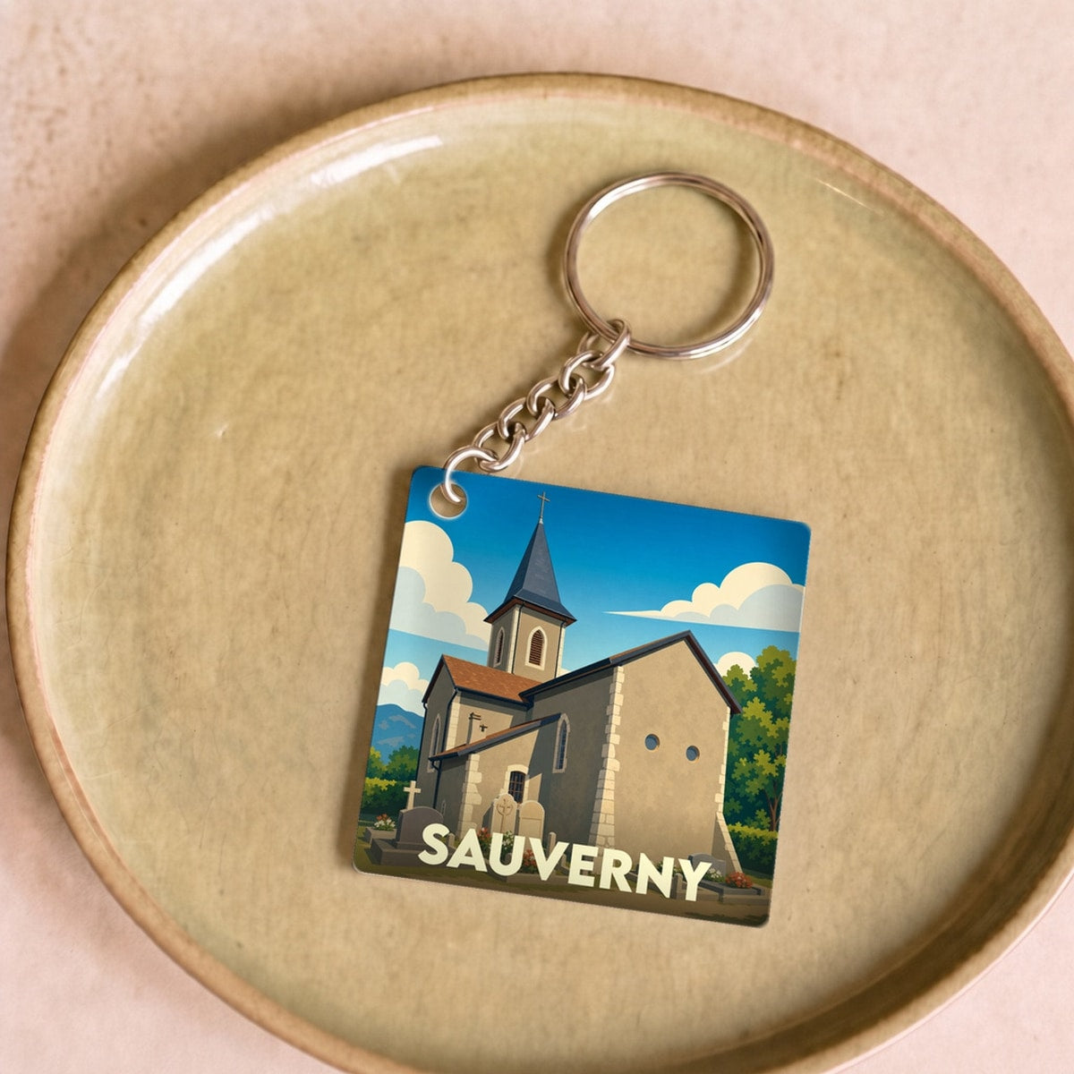 Porte-clés souvenir de la ville de Sauverny avec une illustration stylisée de son église.