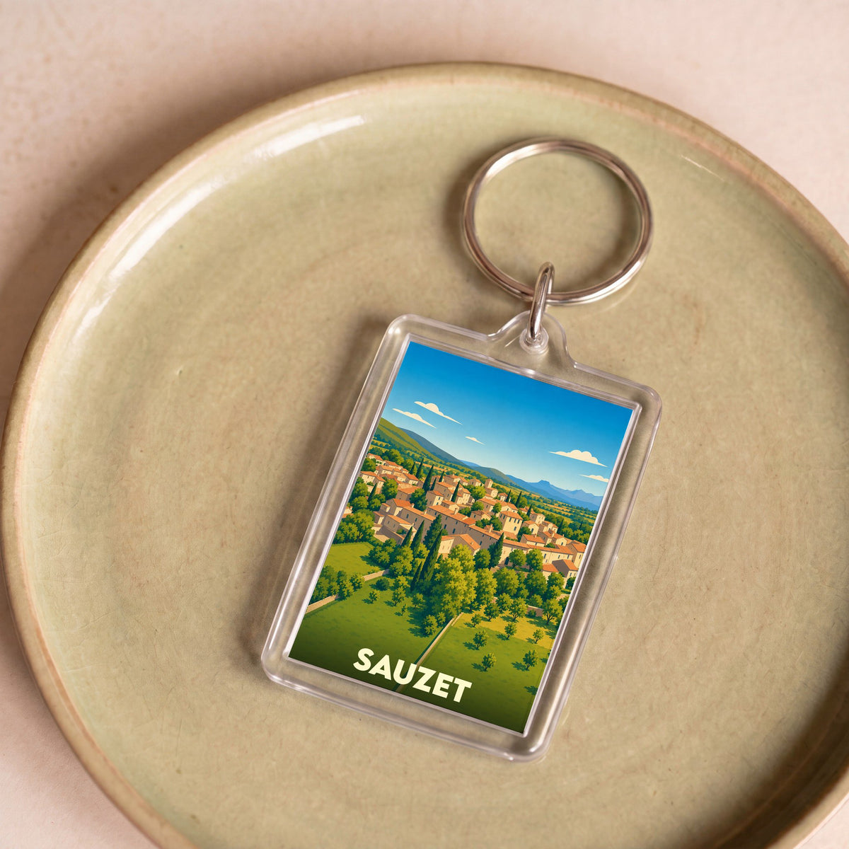 Porte-clés souvenir de la ville de Sauzet avec une illustration stylisée.