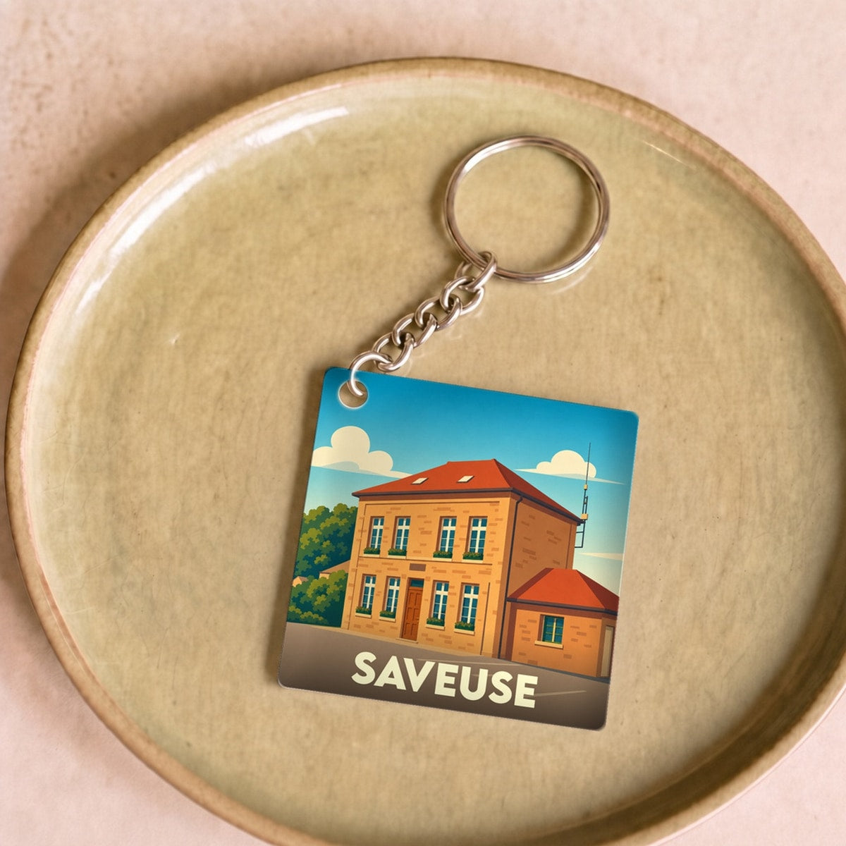 Porte-clés souvenir de la ville de Saveuse avec une illustration stylisée d'un bâtiment local.