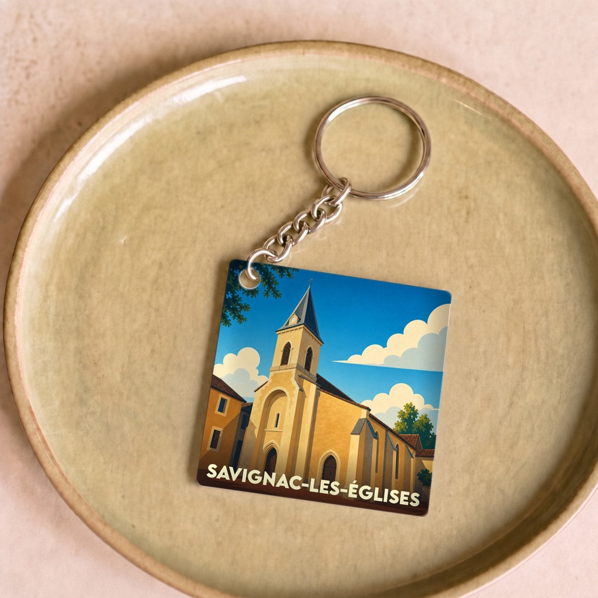 Porte-clés souvenir de la ville de Savignac-les-Églises avec une illustration stylisée de son église.