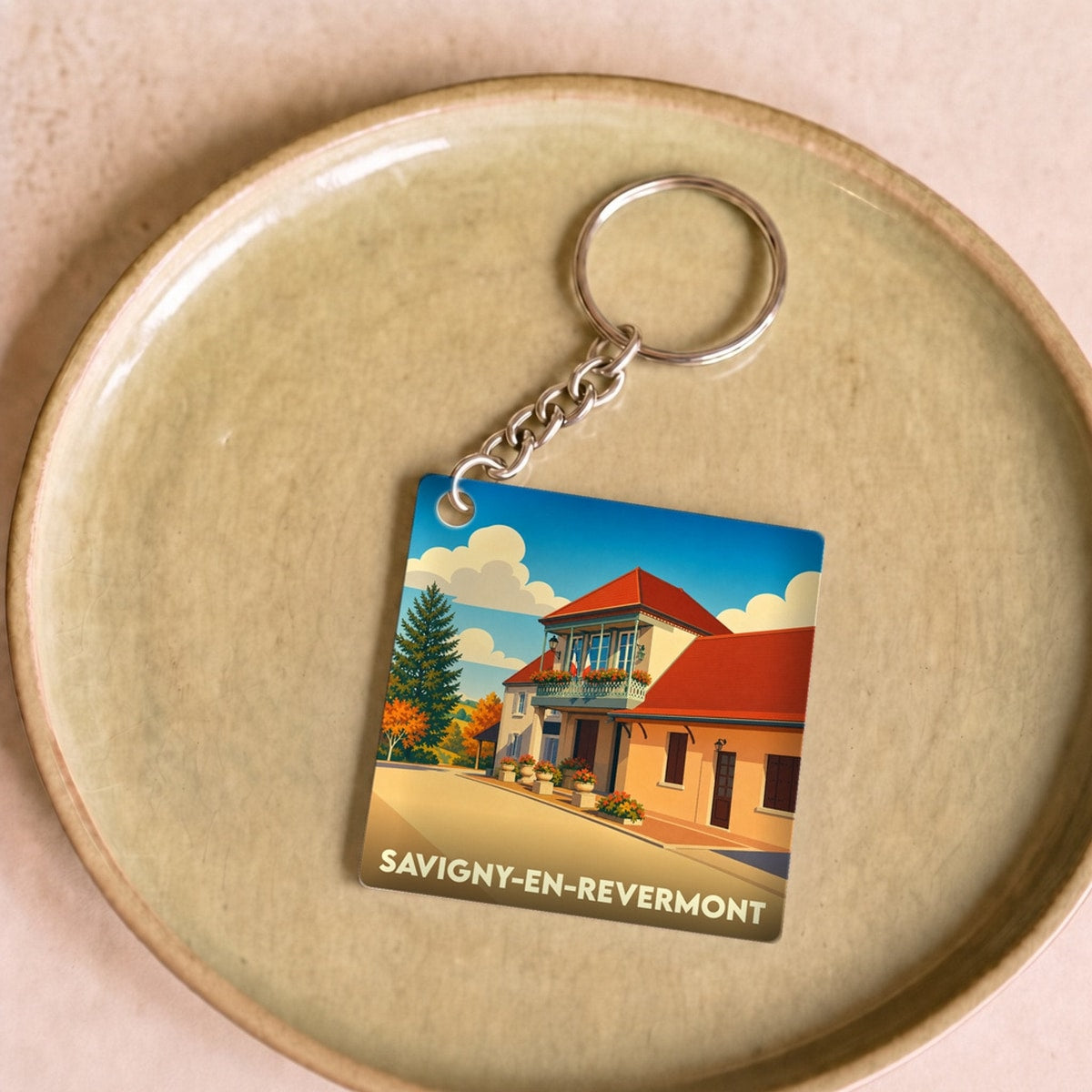 Porte-clés souvenir de la ville de Savigny-en-Revermont avec une illustration stylisée.