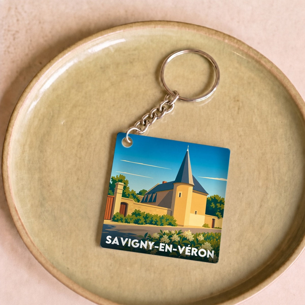Porte-clés souvenir de la ville de Savigny-en-Véron avec une illustration stylisée.