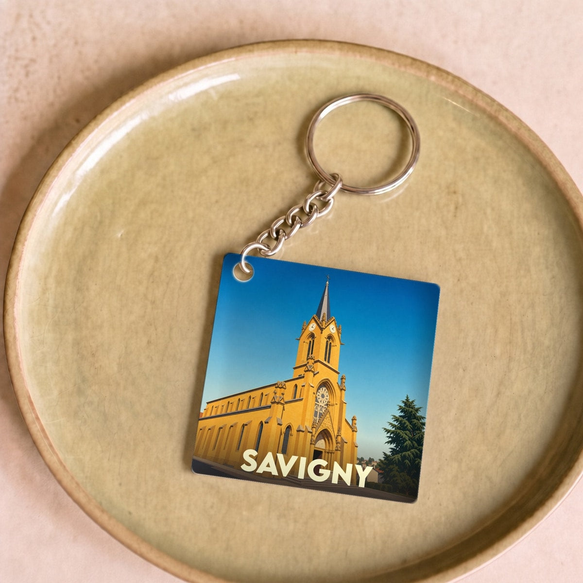 Porte-clés souvenir de la ville de Savigny avec une illustration stylisée de son église.
