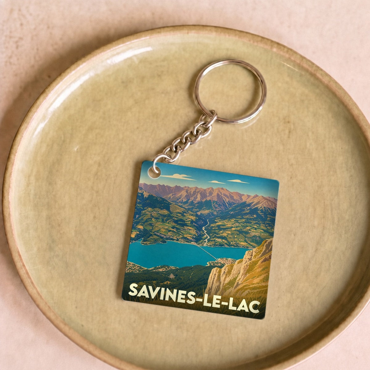 Porte-clés souvenir de la ville de Savines-le-Lac avec une illustration stylisée du lac et des montagnes.