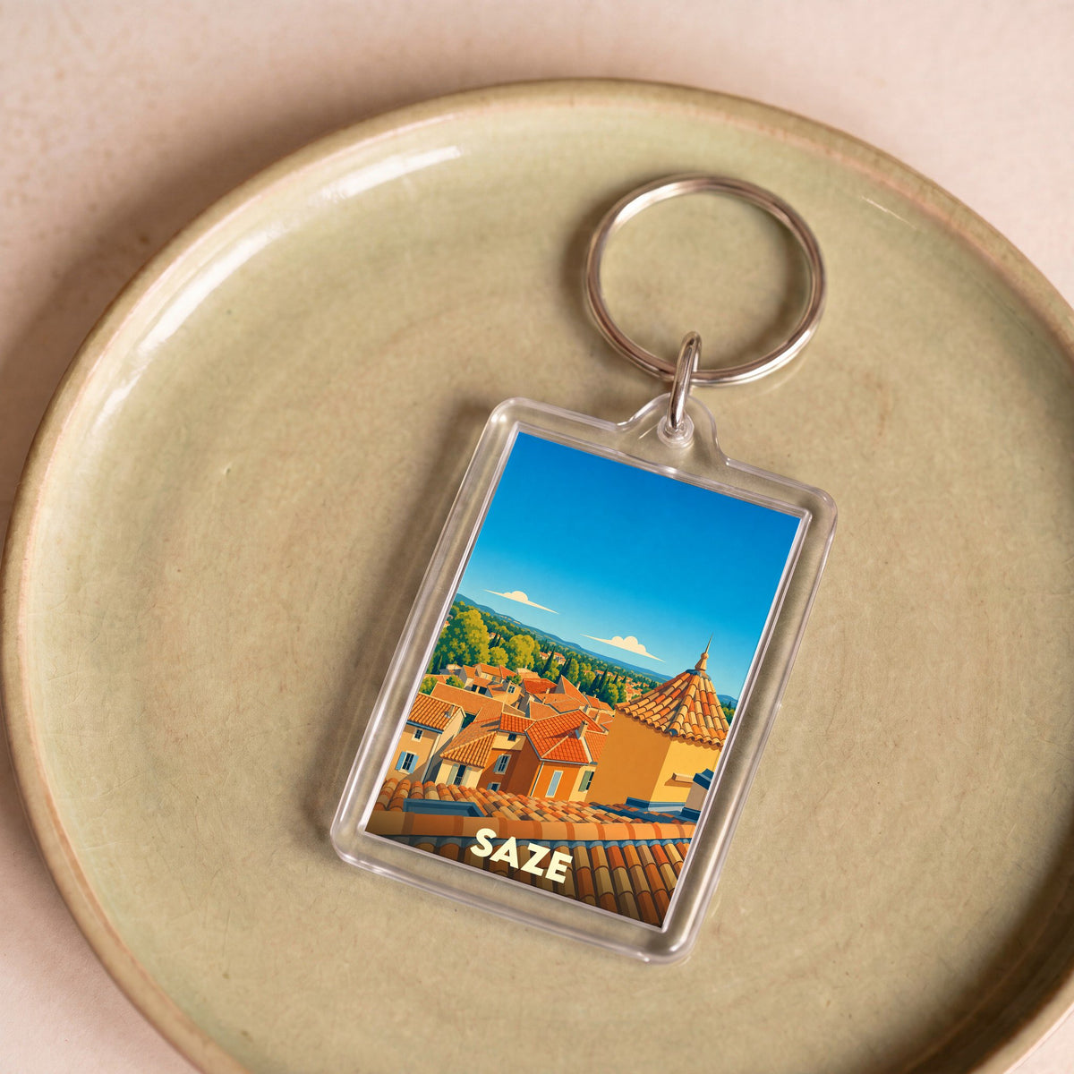 Porte-clés souvenir de la ville de Saze avec une illustration stylisée de ses toits provençaux.