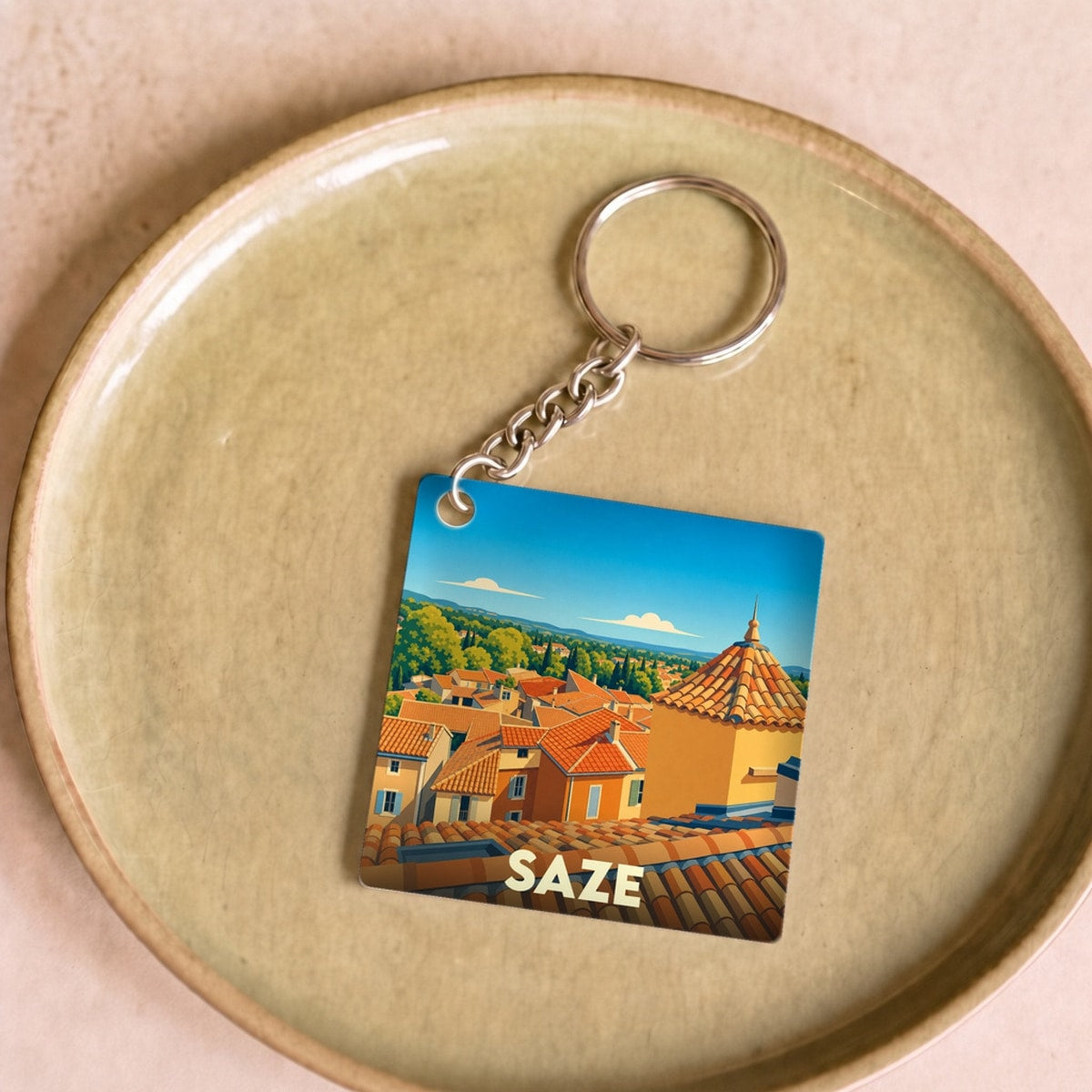 Porte-clés souvenir de la ville de Saze avec une illustration stylisée de ses toits provençaux.