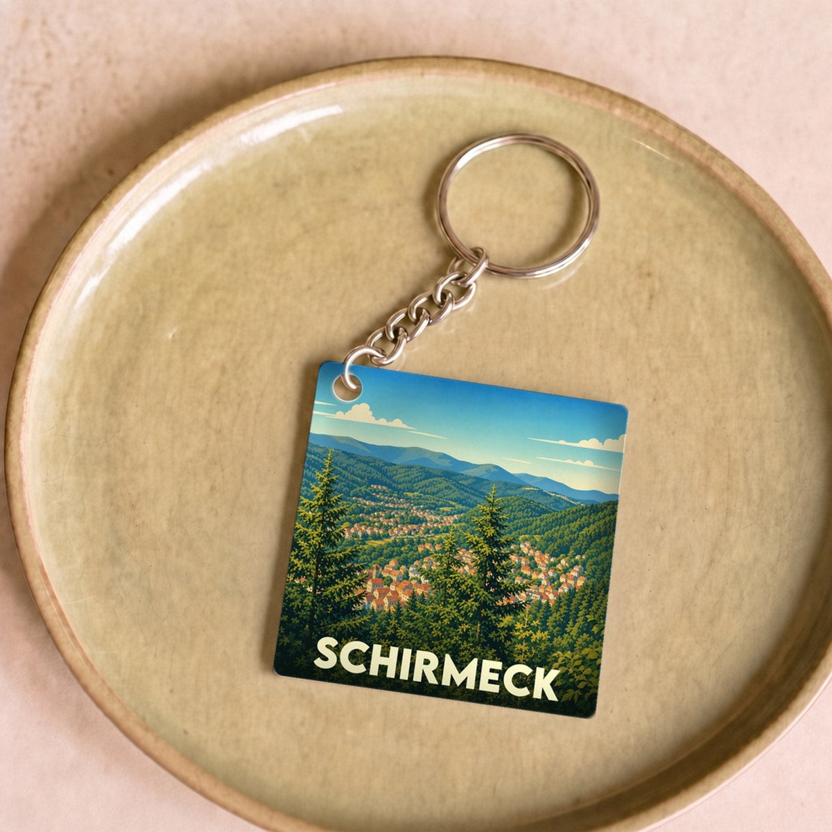 Porte-clés souvenir de la ville de Schirmeck avec une illustration paysagère stylisée.