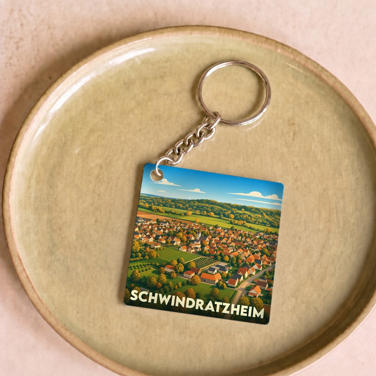 Porte-clés souvenir de la ville de Schwindratzheim avec une illustration paysagère stylisée.