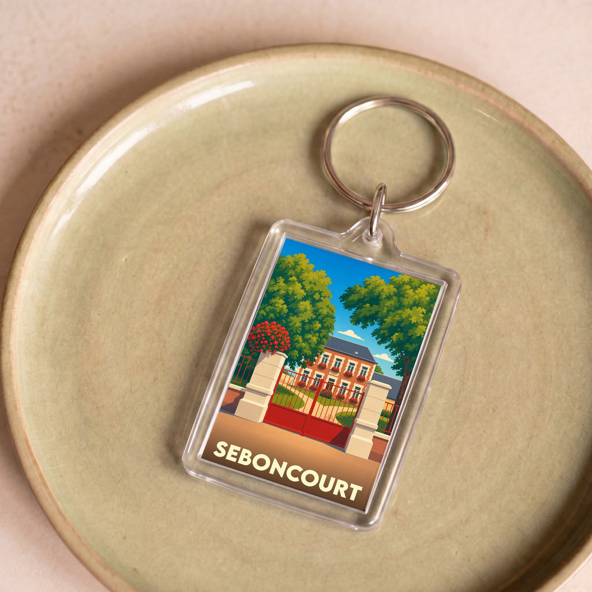 Porte-clés souvenir de la ville de Seboncourt avec une illustration stylisée d'une demeure bourgeoise.