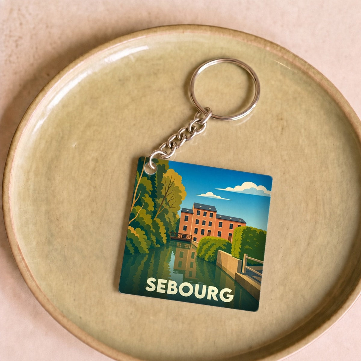 Porte-clés souvenir de la ville de Sebourg avec une illustration stylisée.