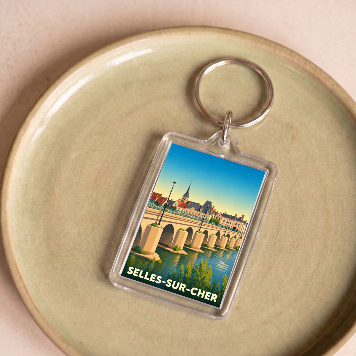 Porte-clés souvenir de la ville de Selles-sur-Cher avec une illustration stylisée de son pont et de son église.