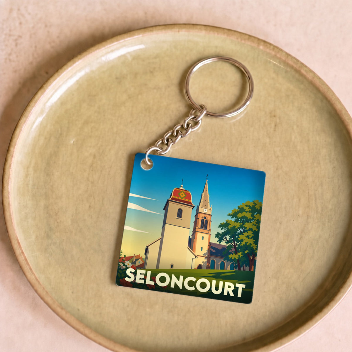 Porte-clés souvenir de la ville de Seloncourt avec une illustration stylisée.