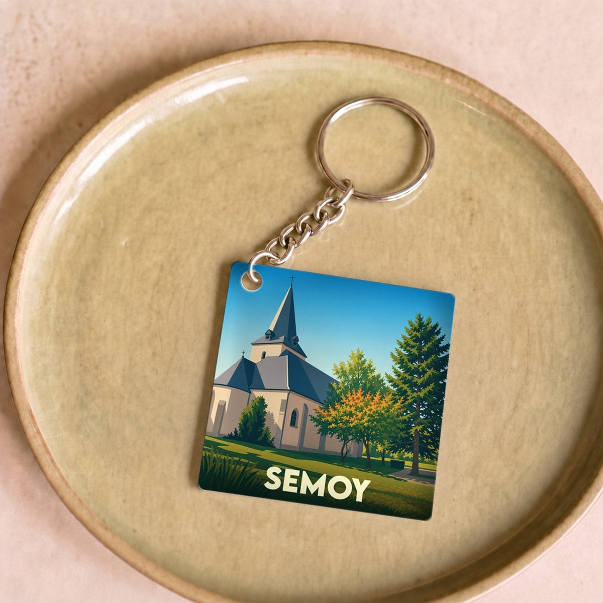 Porte-clés souvenir de la ville de Semoy avec une illustration stylisée d'une église sous un ciel bleu.