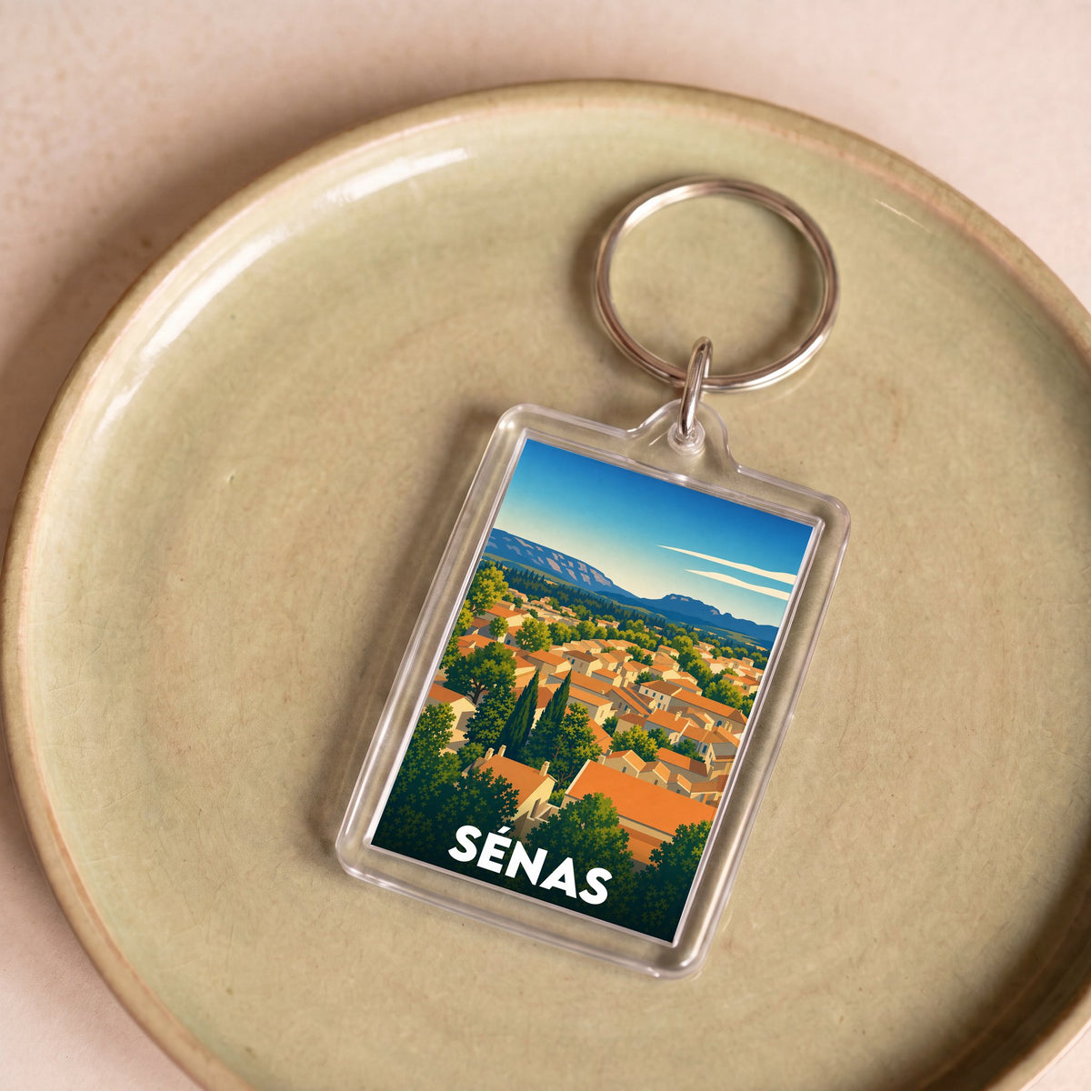 Porte-clés souvenir de la ville de Sénas avec une illustration stylisée de ses paysages provençaux.