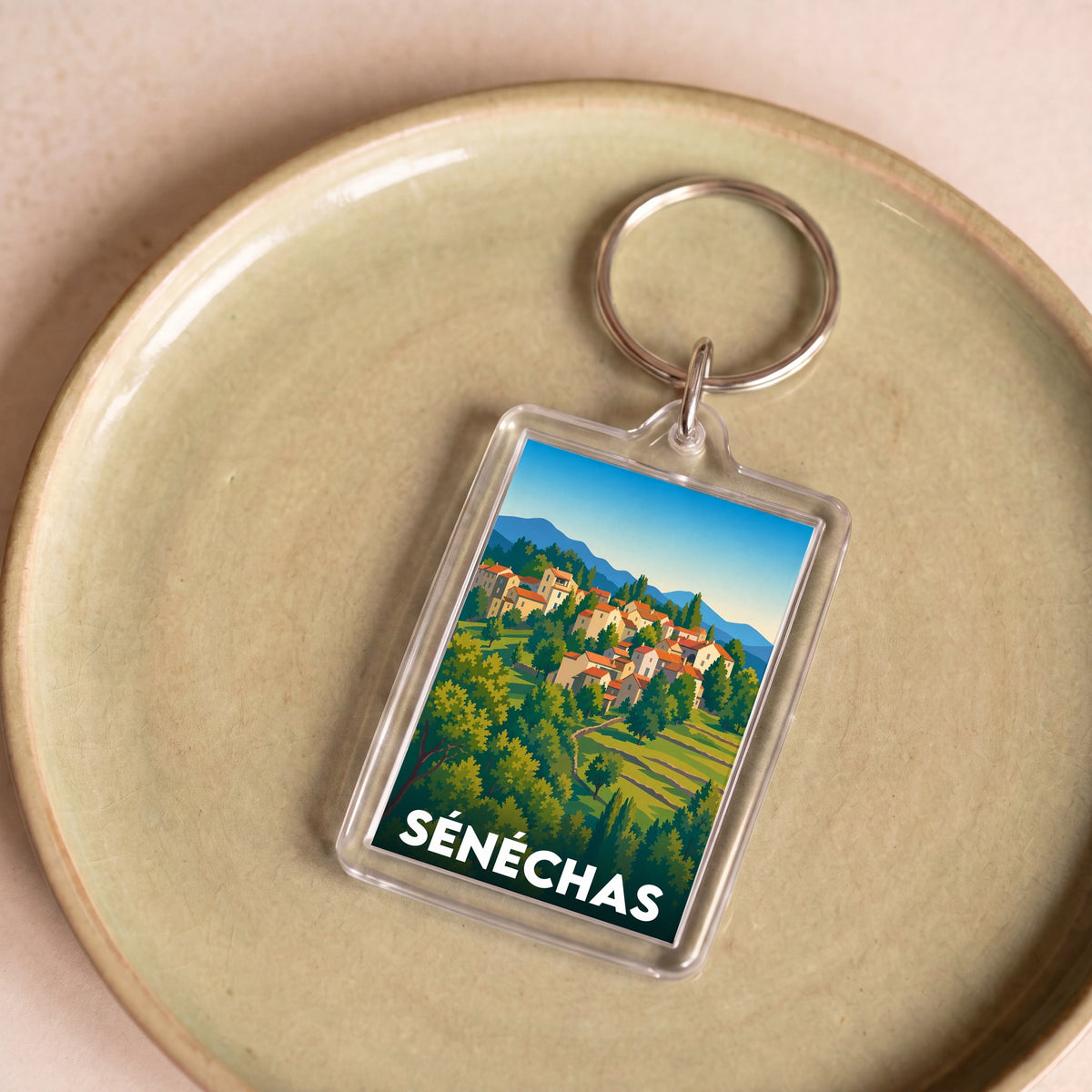 Porte-clés souvenir de la ville de Sénéchas avec une illustration stylisée du village.