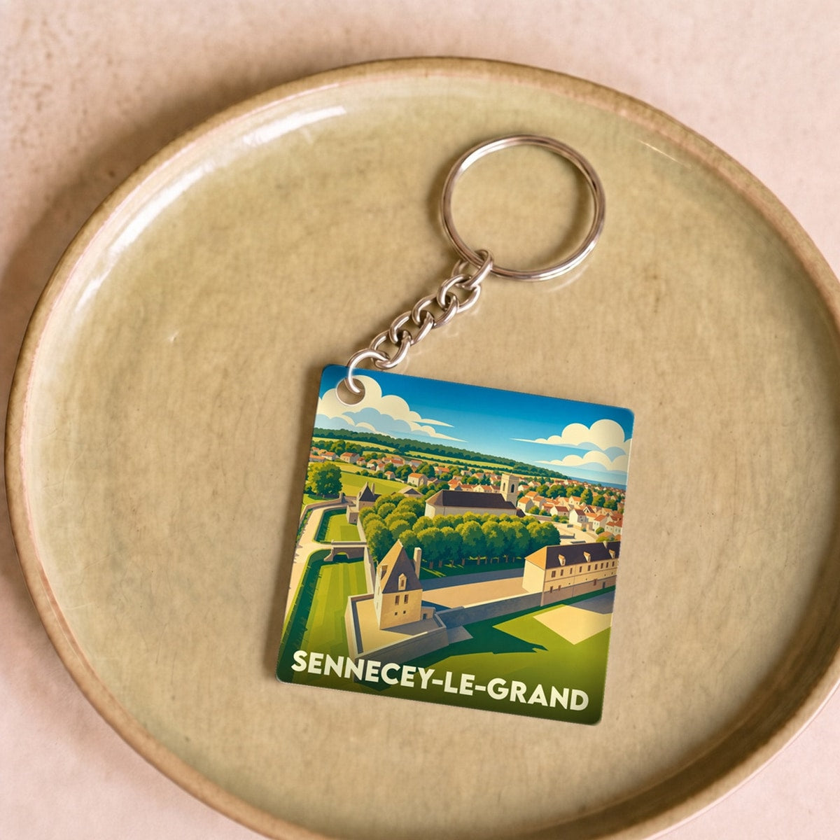 Porte-clés souvenir de Sennecey-le-Grand illustré d'un dessin stylisé de la ville et de son château.