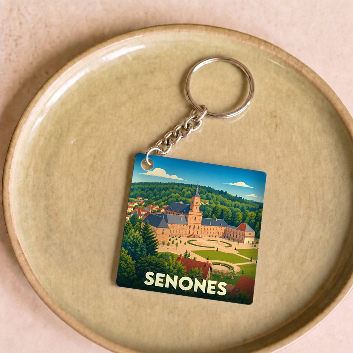 Porte-clés souvenir de la ville de Senones avec une illustration stylisée de son abbaye.