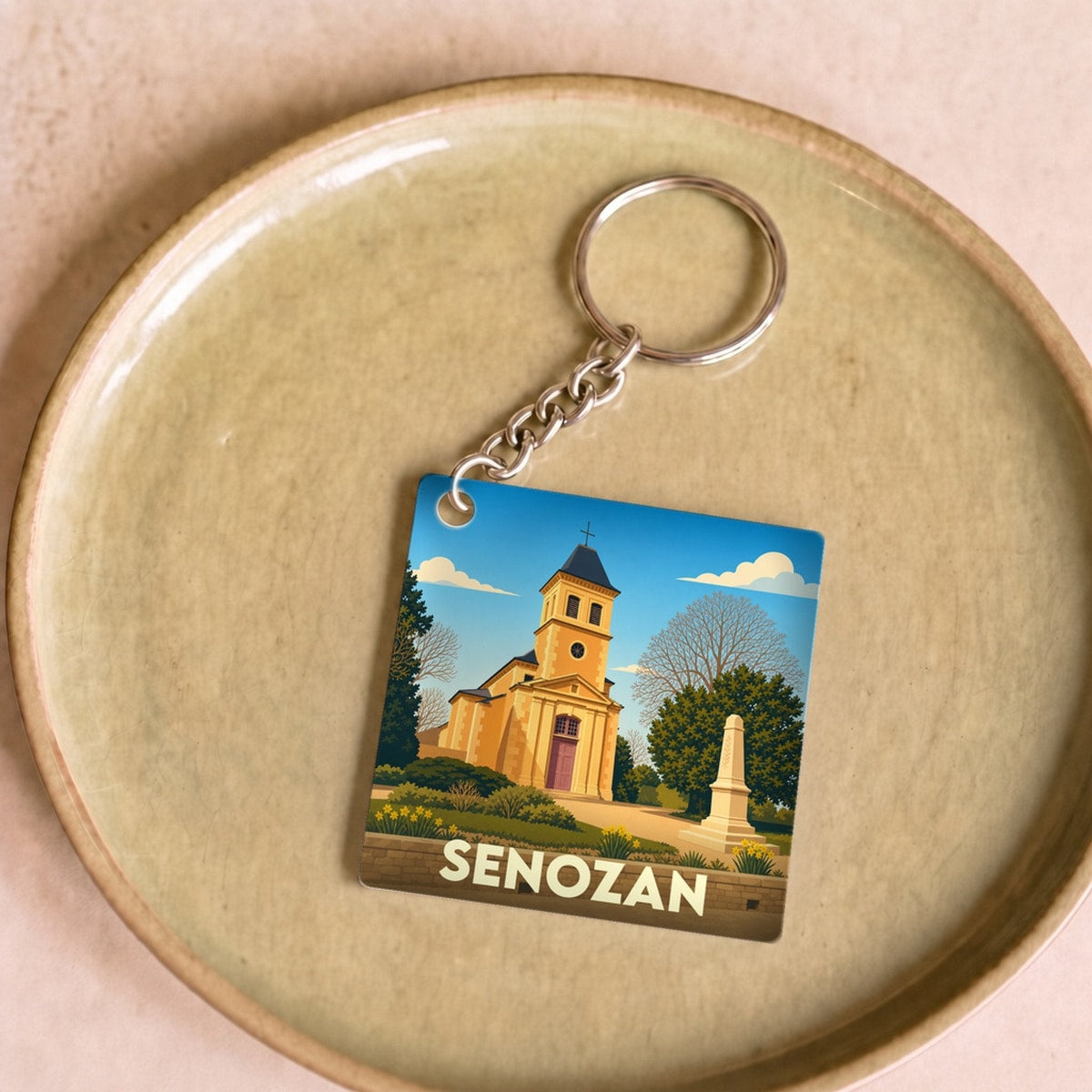 Porte-clés souvenir de la ville de Senozan avec une illustration stylisée de son église.