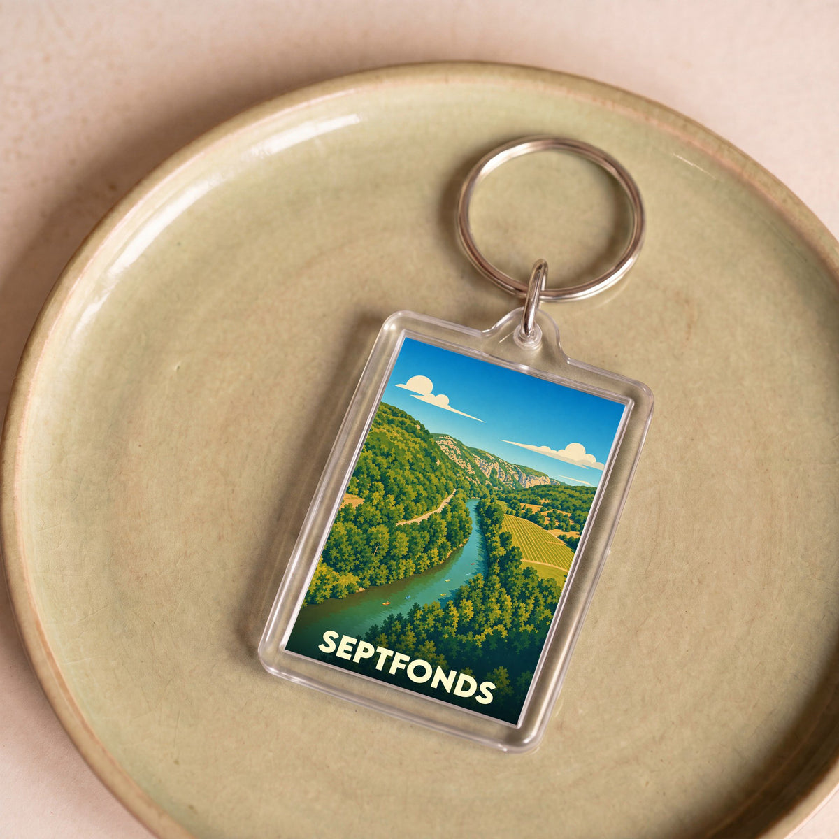 Porte-clés souvenir de la ville de Septfonds avec une illustration stylisée d'un paysage de rivière et de collines.