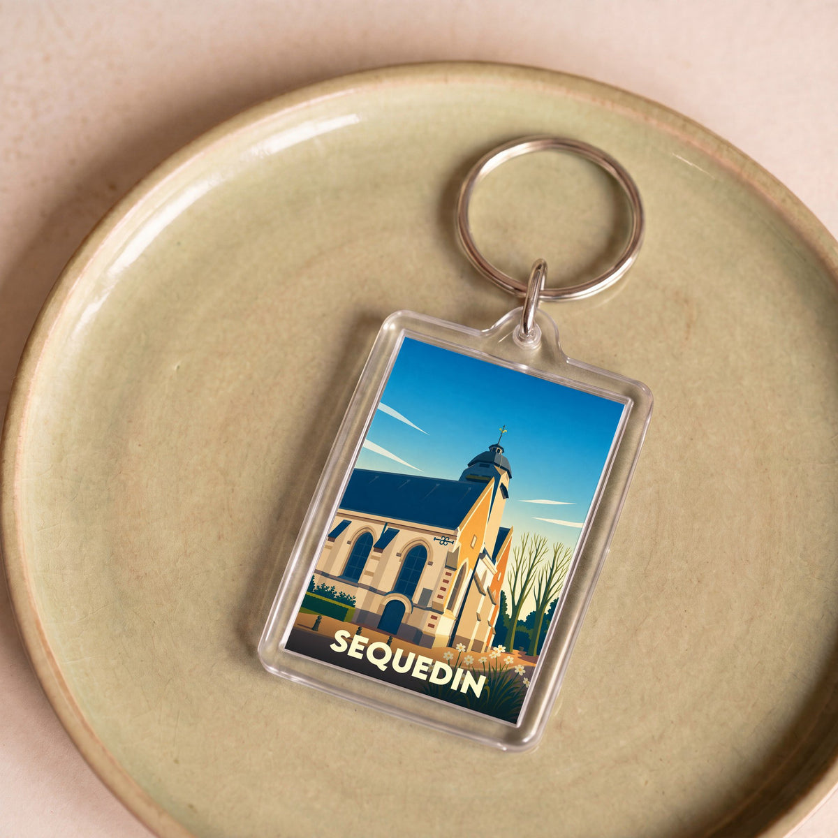Porte-clés souvenir de la ville de Sequedin avec une illustration stylisée de son église.