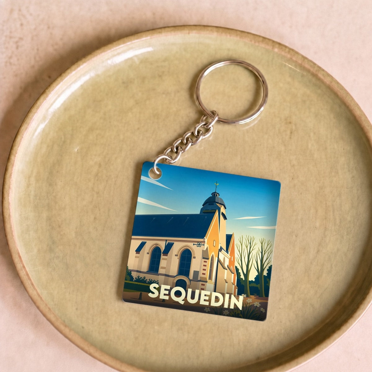 Porte-clés souvenir de la ville de Sequedin avec une illustration stylisée de son église.