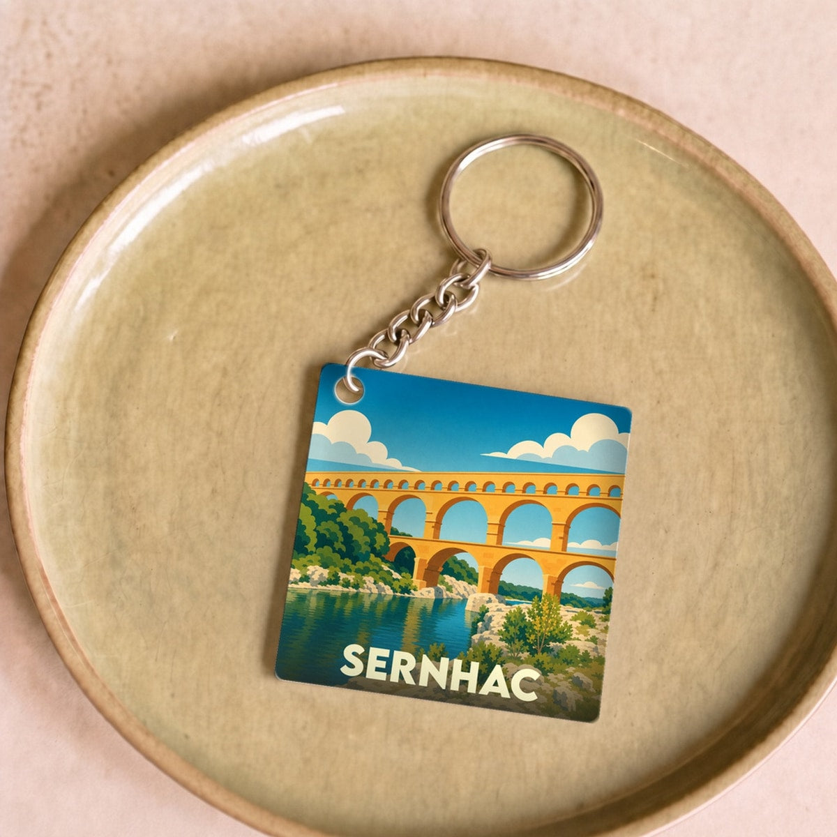 Porte-clés souvenir de la ville de Sernhac avec une illustration stylisée du Pont du Gard.