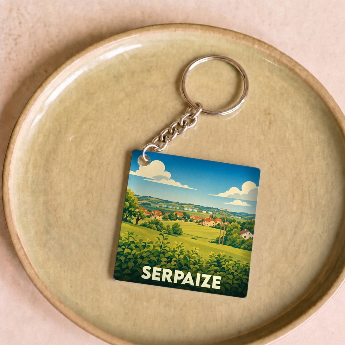 Porte-clés souvenir de la ville de Serpaize avec une illustration stylisée de son paysage rural.