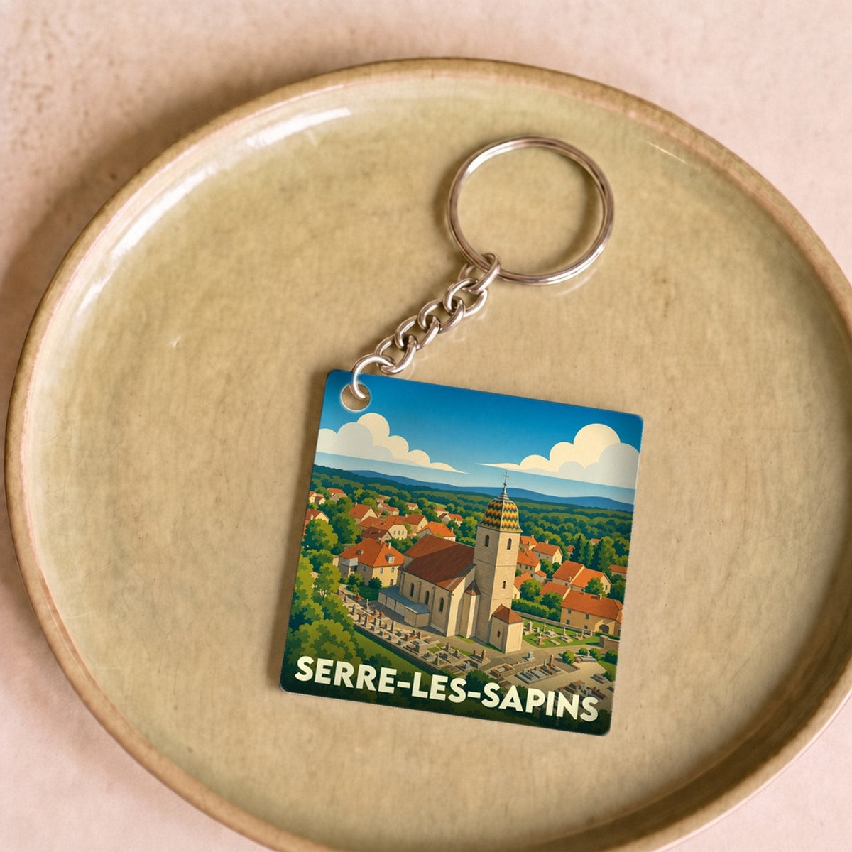Porte-clés souvenir de la ville de Serre-les-Sapins avec une illustration stylisée.