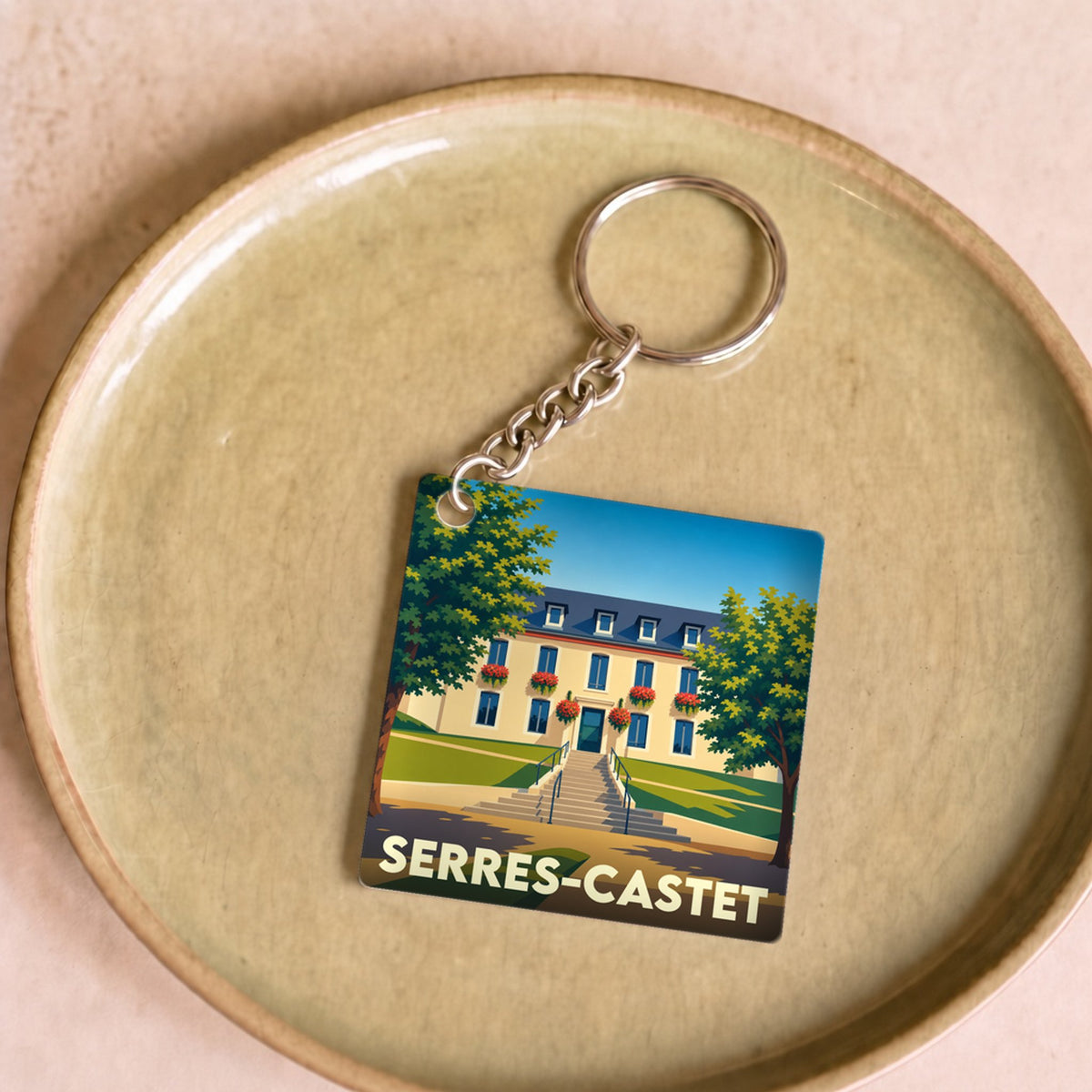 Porte-clés souvenir de la ville de Serres-Castet avec une illustration stylisée de sa mairie.