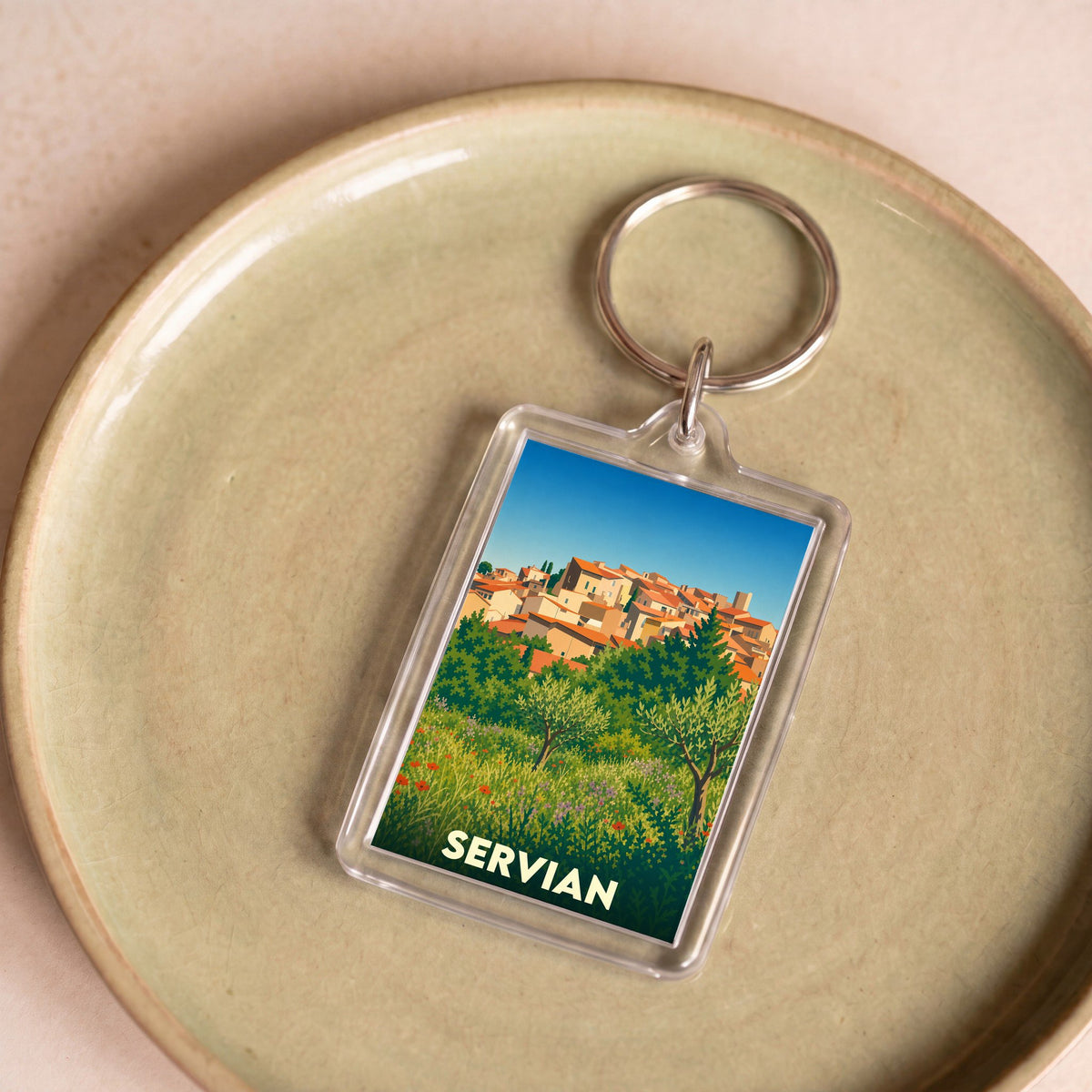 Porte-clés souvenir de la ville de Servian avec une illustration stylisée d'un paysage méditerranéen.
