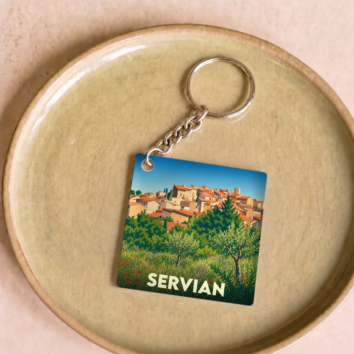 Porte-clés souvenir de la ville de Servian avec une illustration stylisée d'un paysage méditerranéen.
