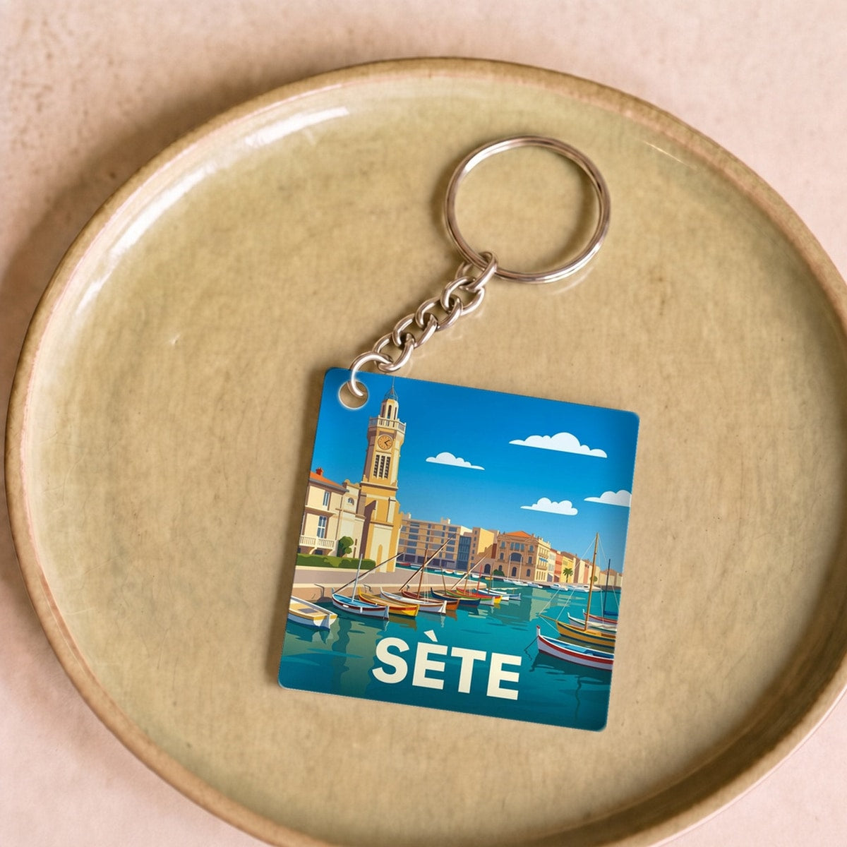 Porte-clés souvenir de la ville de Sète avec une illustration stylisée du port.