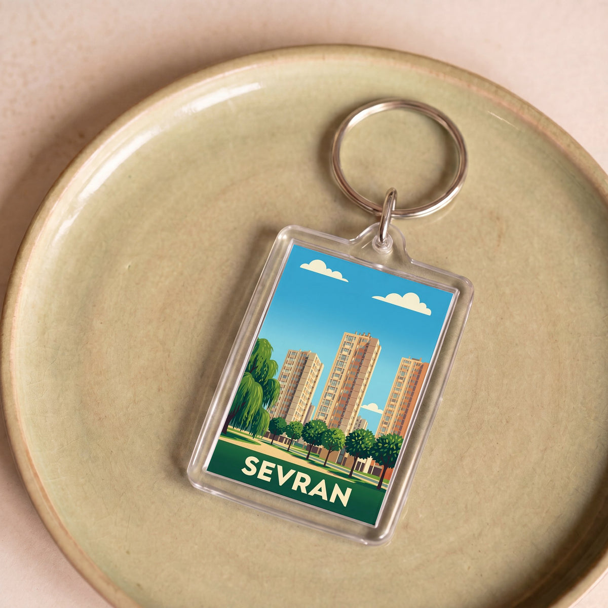 Porte-clés souvenir de la ville de Sevran avec une illustration stylisée de son paysage urbain.