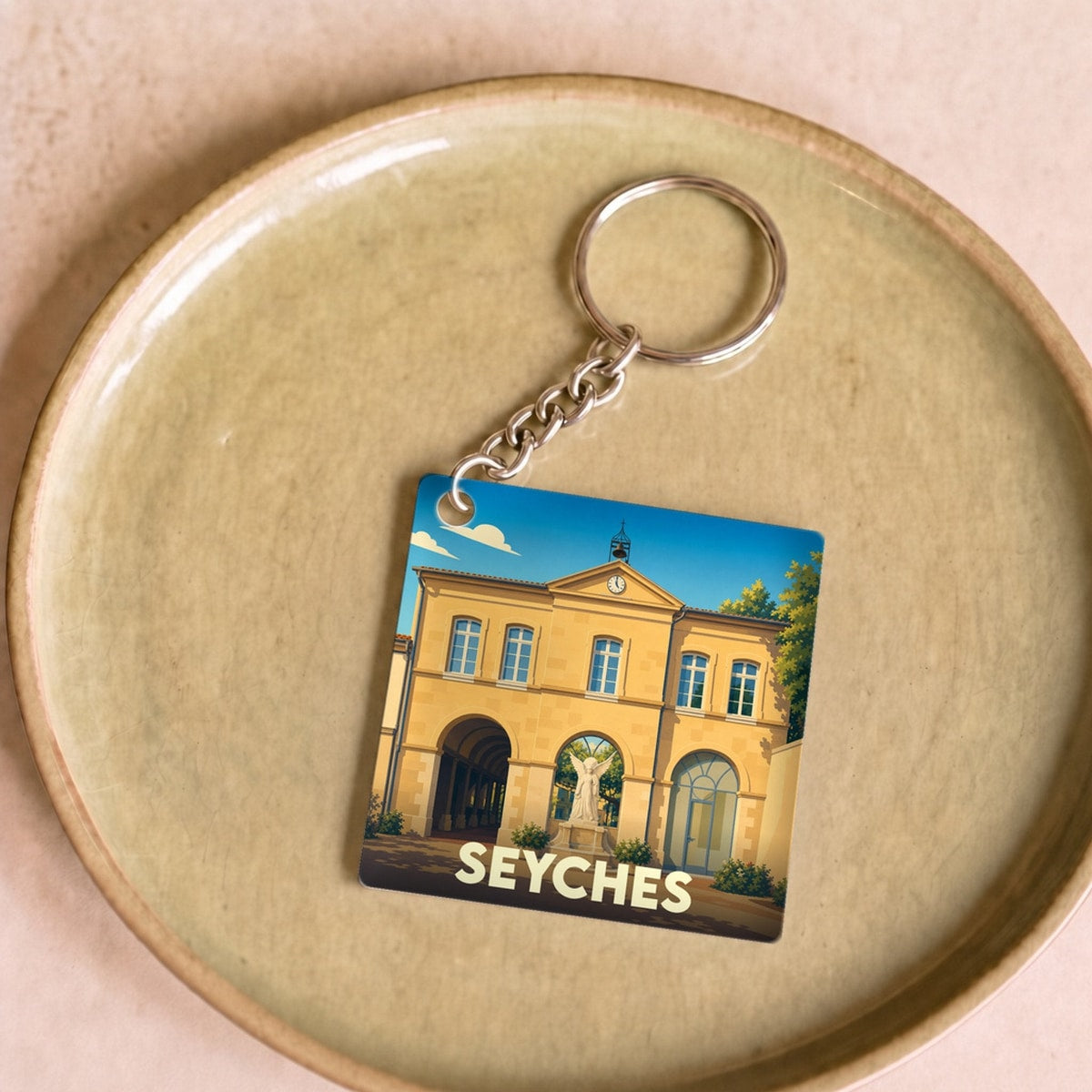 Porte-clés souvenir de la ville de Seyches avec une illustration stylisée d'un bâtiment historique.