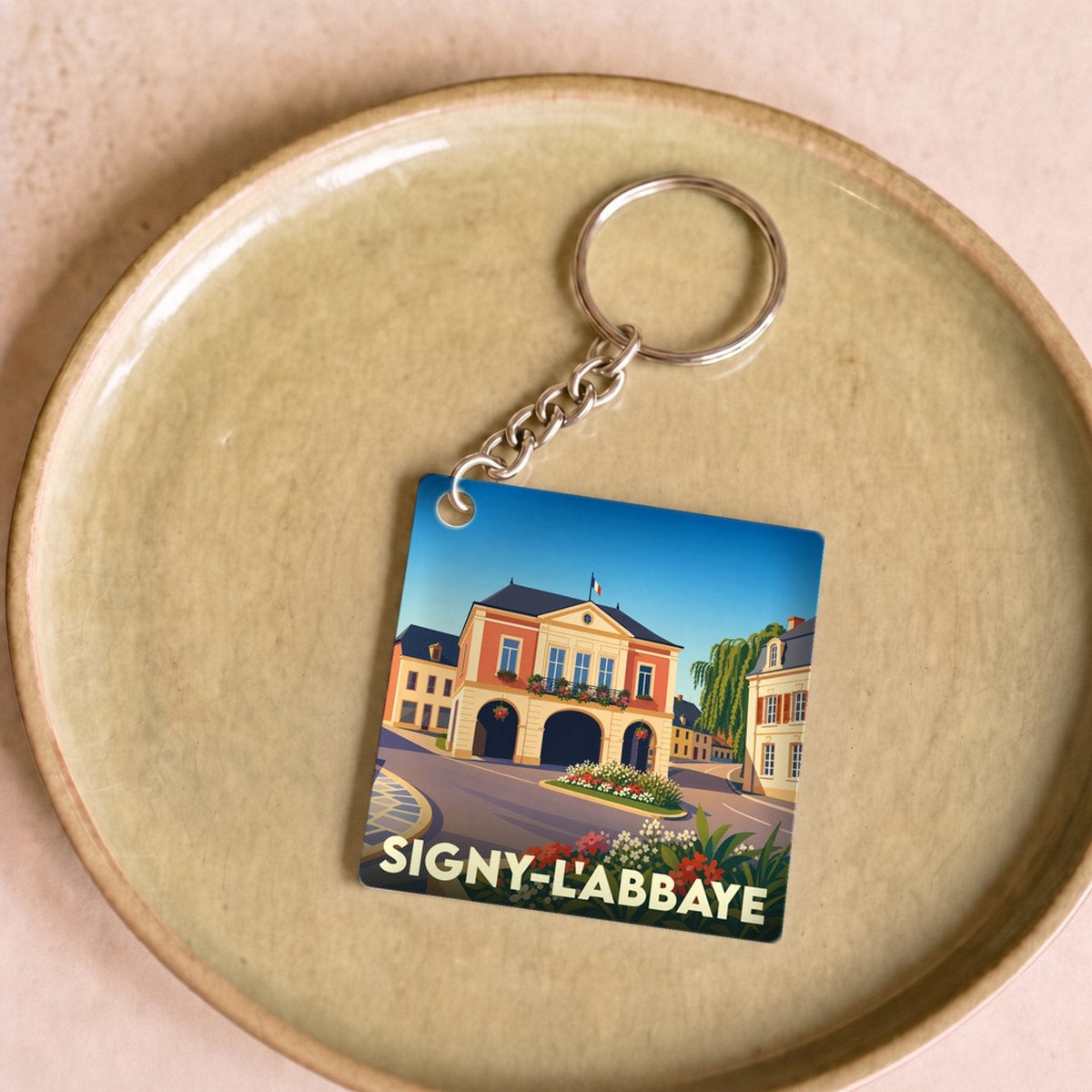 Porte-clés souvenir de la ville de Signy-l'Abbaye avec une illustration stylisée.