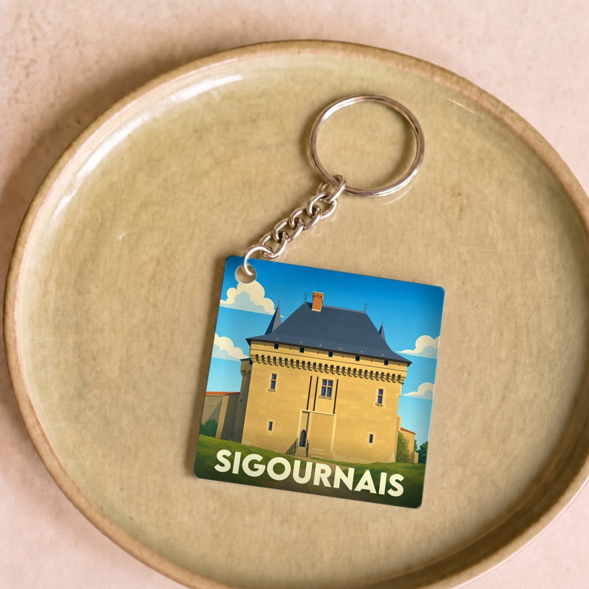 Porte-clés souvenir de la ville de Sigournais avec une illustration stylisée de son château.