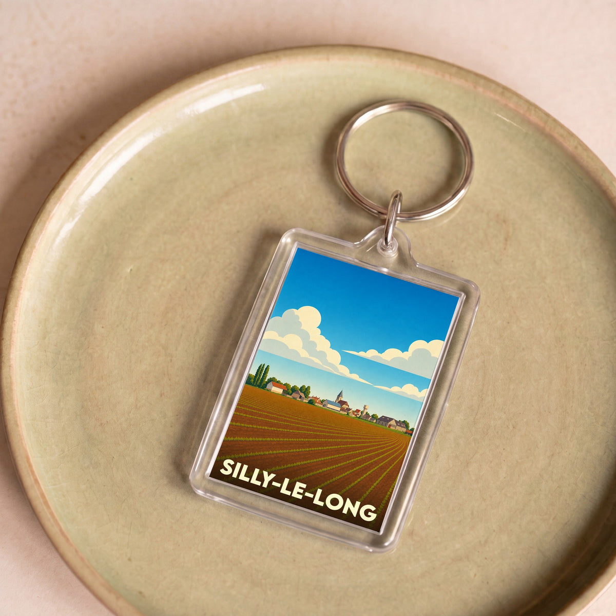 Porte-clés souvenir de la ville de Silly-le-Long avec une illustration stylisée d'un paysage champêtre.