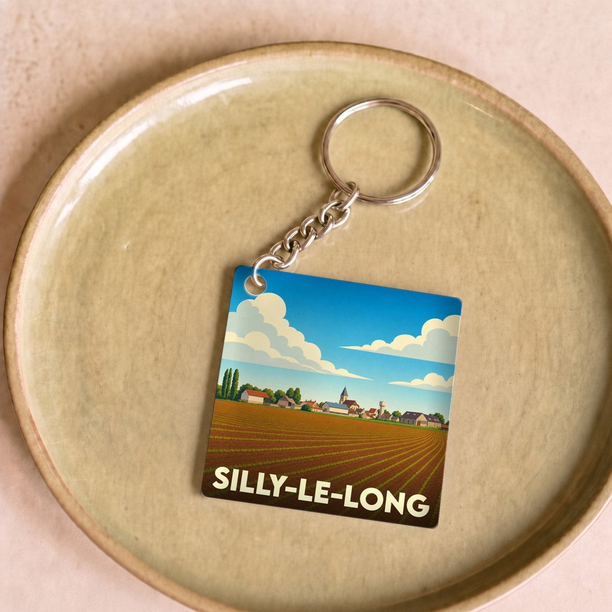 Porte-clés souvenir de la ville de Silly-le-Long avec une illustration stylisée d'un paysage champêtre.