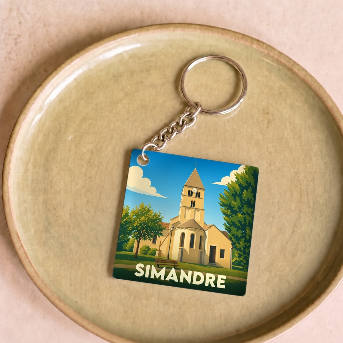 Porte-clés souvenir de la ville de Simandre avec une illustration stylisée de son église.